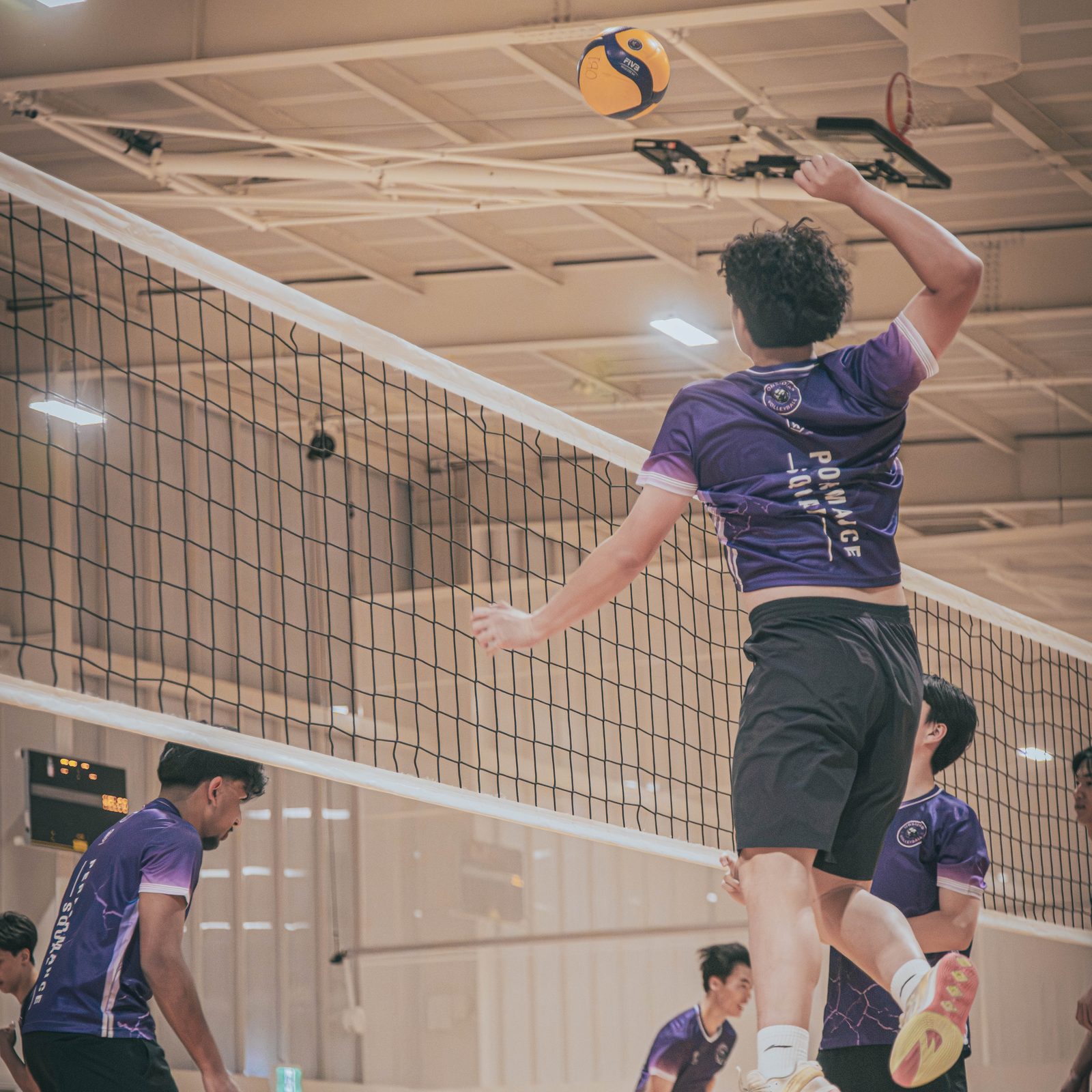 Player in purple Obsidian kit attacking at the net while two teammates block during a West Ryde session