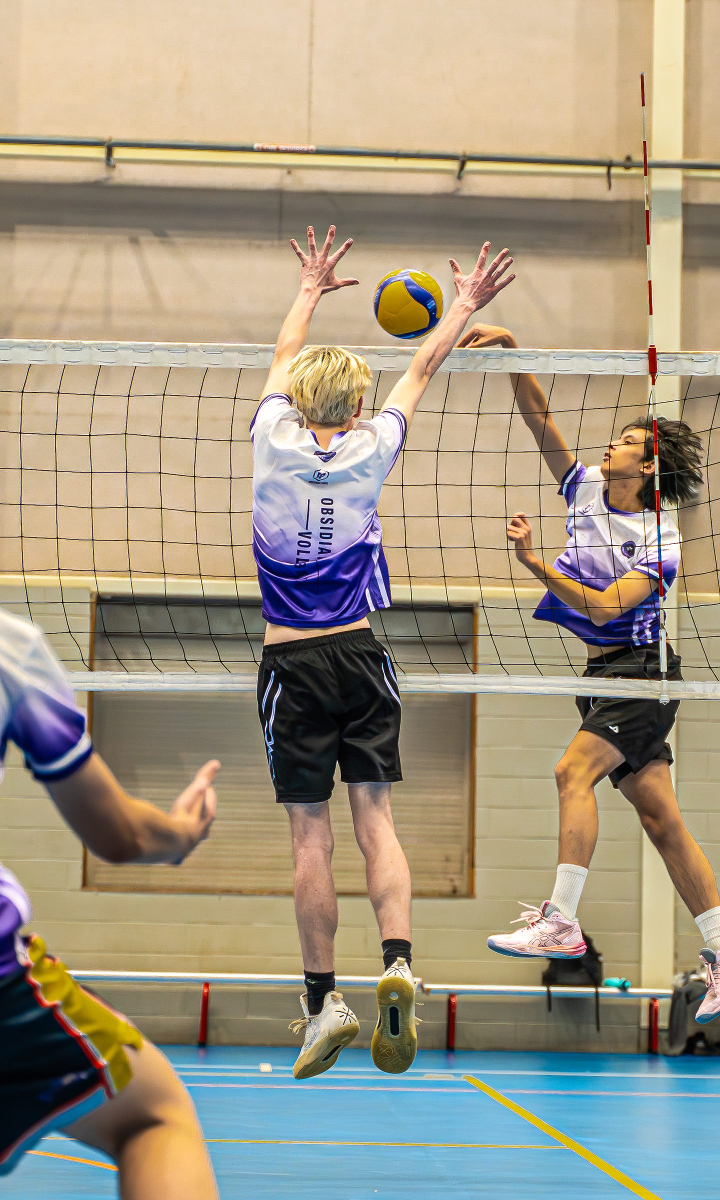 Two Obsidian players jump to block at the net on the blue courts at Sydney Olympic Park Sports Halls